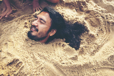 High angle view of man buried in sand at beach