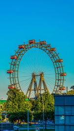 Low angle view of ferris wheel against clear blue sky