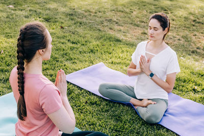 Two young women in the park doing yoga. exercising outdoors, healthy lifestyle