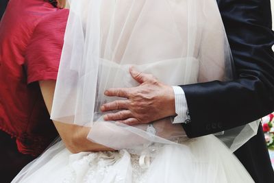 Rear view of man and woman embracing bride