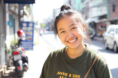 Portrait of smiling young woman on street in city