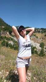 Young woman wearing sunglasses on field against clear sky