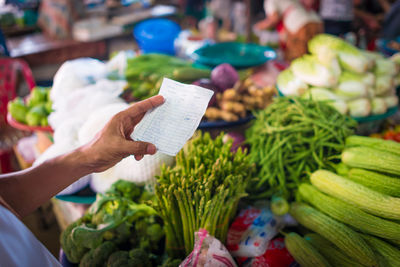 Hand holding vegetables at market stall