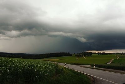 Road amidst field against sky