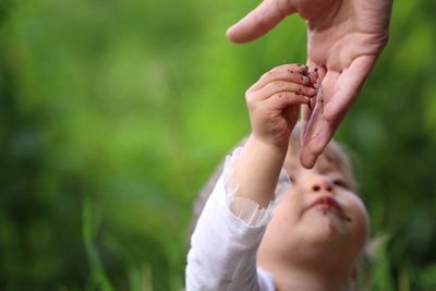 Baby girl giving root vegetable to parent at field