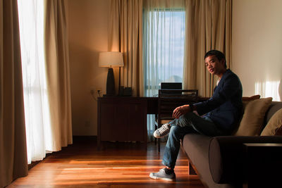 Side view of young man sitting at home