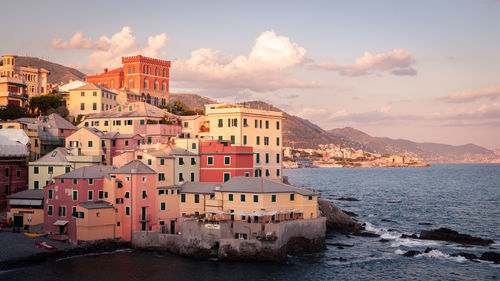 Buildings by sea against sky in town