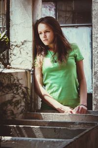 Portrait of beautiful young woman standing against wall