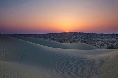 Scenic view of desert against clear sky during sunset