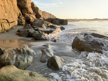 Rocks on sea shore against sky
