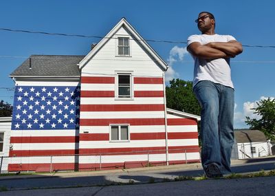 Full length of man standing against american flag patterned house