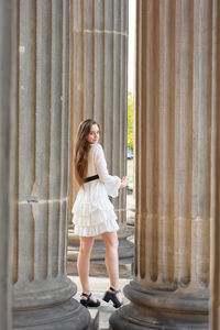 Portrait of young woman standing against columns