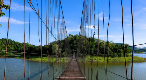 Footbridge over river against sky