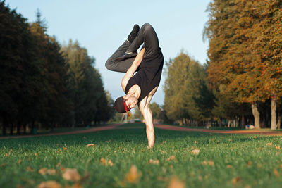 Man skateboarding on field against trees during autumn