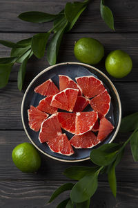 High angle view of sliced grapefruit on the plate and green leaves on table