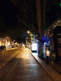 Illuminated street light on sidewalk at night