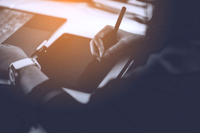 Midsection of woman using graphics tablet at desk in office