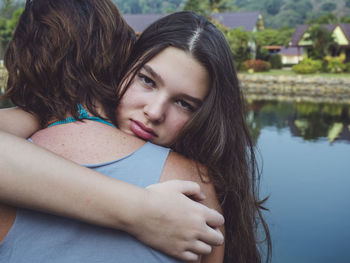 Portrait of sad daughter embracing mother while standing outdoors