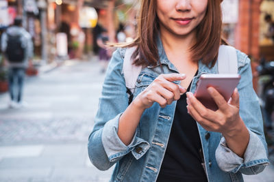 Young woman using mobile phone on street in city