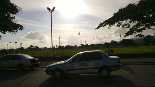Cars on road against cloudy sky