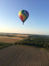 Hot air balloons flying over field against sky