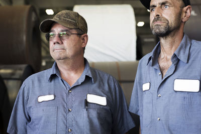 Manual workers looking away while standing in metal steel mill