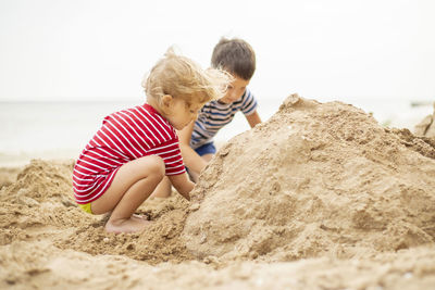 Full length of boy playing with sand at beach