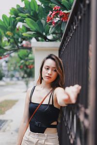 Young woman standing by gate