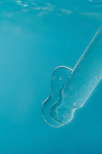 Pipette with cosmetic product in water with bubbles.