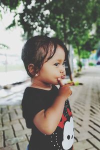 Portrait of cute boy looking away while standing outdoors