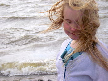 Girl with tousled hair standing on shore