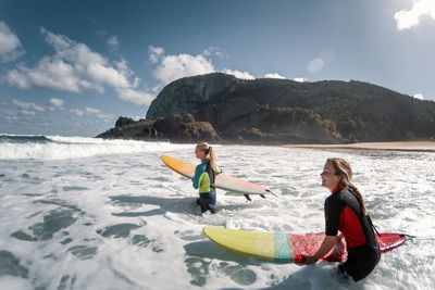 Women with surfboards entering the water