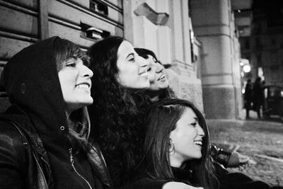 Close-up of female friends smiling while sitting outdoors at night