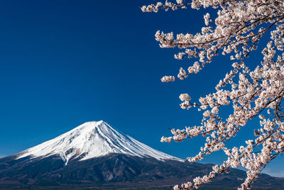 Low angle view of snow covered mountain against blue sky