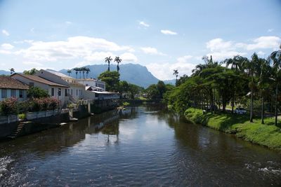 Scenic view of river by buildings against sky