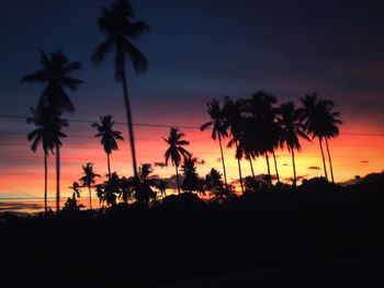 Silhouette palm trees against romantic sky at sunset