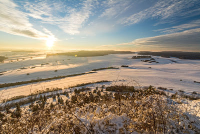 Scenic view of snow covered land against sky during sunset