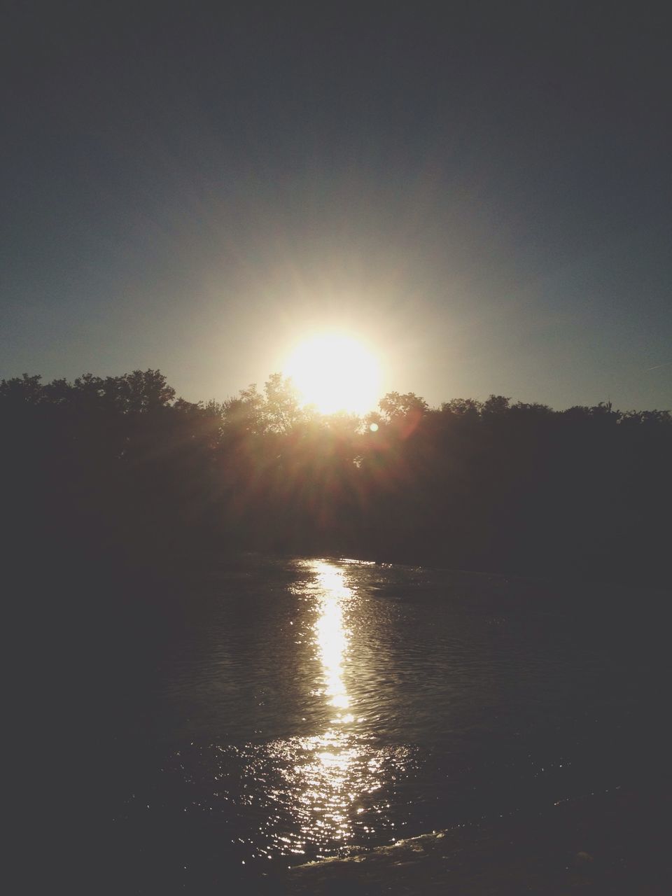 water, sun, tranquil scene, tranquility, scenics, reflection, beauty in nature, sunset, tree, waterfront, silhouette, lake, sunlight, nature, sky, idyllic, sunbeam, lens flare, river, rippled