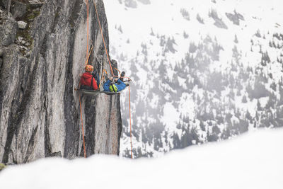 Rock climbers rest on a portaledge during a multi-day climbing trip.