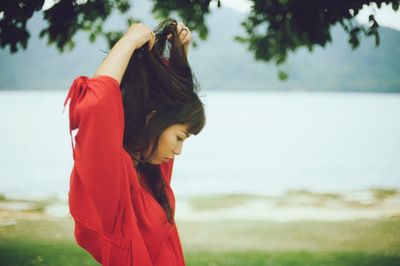 Side view of woman holding hair standing at park