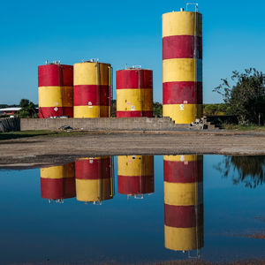 Multi colored fuel tanks reflecting on a puddle