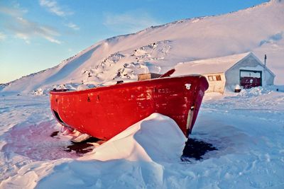 Red umbrella on snowcapped mountain against sky