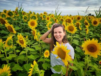 Portrait of smiling woman with sunflower in field