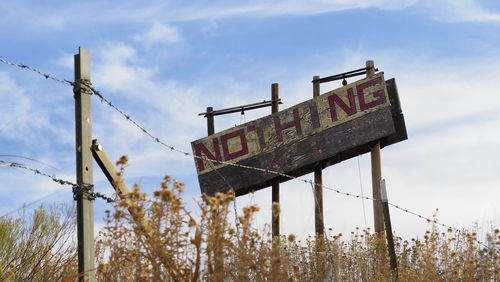 Low angle view of information sign against sky