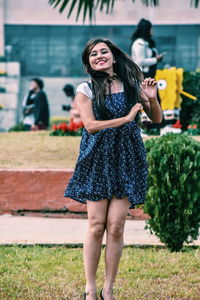 Portrait of happy young woman standing in park