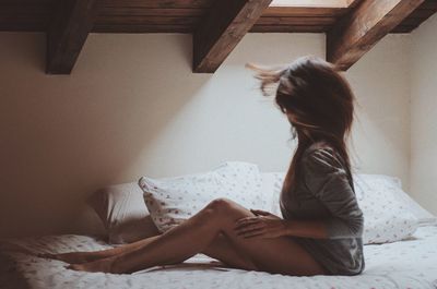 Side view of woman on bed at home