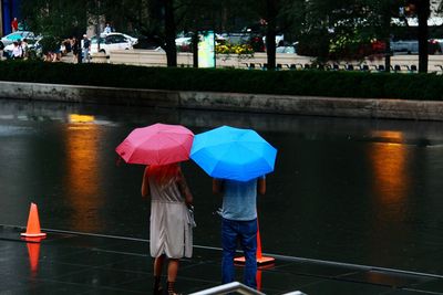 Rear view of people with umbrella walking on water