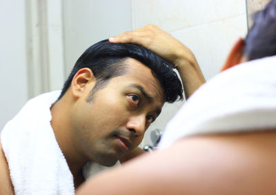 Close-up of man looking his reflection in mirror at bathroom