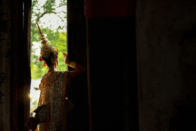 Side view of man standing by window