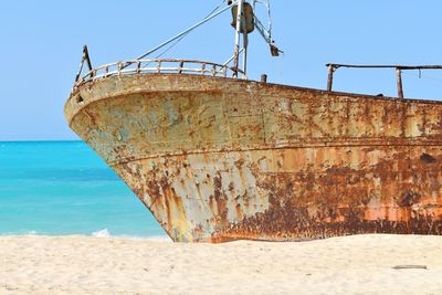 Abandoned ship on beach against clear sky